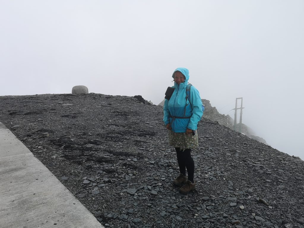 Agata in dicht gepackter Jacke auf der nebligen Spitze des Berges Scopi